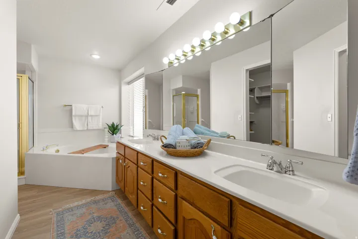 Dual vanity with wood cabinetry and chrome hardware, integrated sinks, and a large wall-mounted mirror