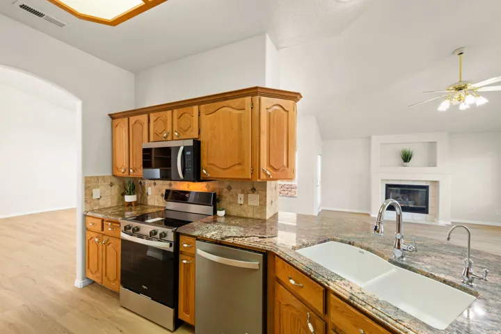 BRAND NEW STAINLESS APPLIANCES - Kitchen featuring wood cabinetry with brass hardware, granite countertops, tile backsplash, and stainless steel appliances