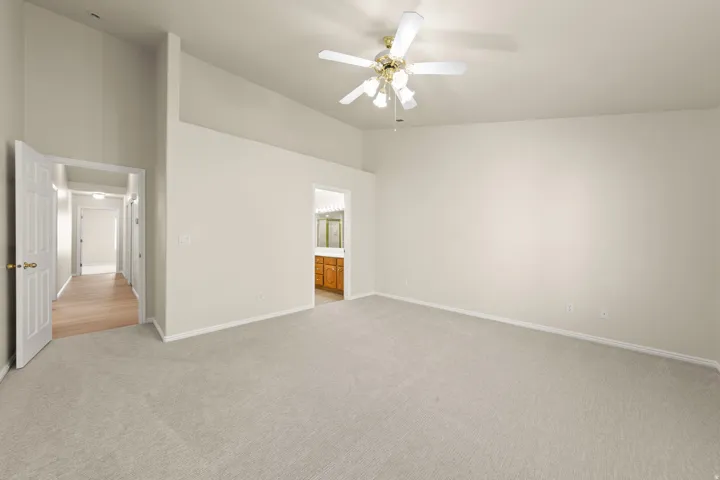 PRIMARY - Spacious room featuring vaulted ceilings, light neutral wall tones, and plush carpeting