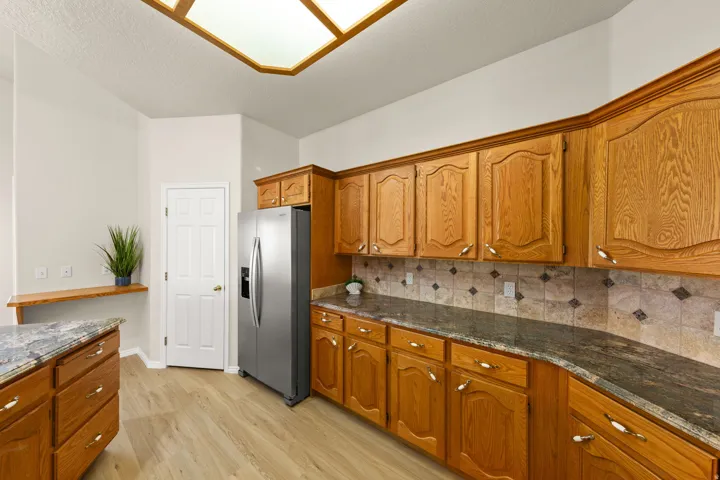 BRAND NEW STAINLESS APPLIANCES - Kitchen featuring extensive wood cabinetry, granite-finish countertops, and a tiled backsplash with diamond accents