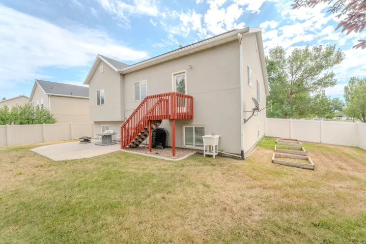 Expansive backyard featuring a concrete patio, privacy fencing, and raised garden beds