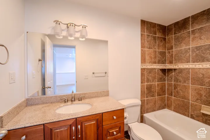 Bathroom featuring a wood vanity with an integrated sink, a light-toned countertop, and brushed nickel fixtures
