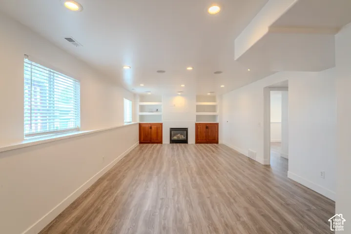 Spacious lower-level area featuring recessed lighting, light wood-finish flooring, and white walls