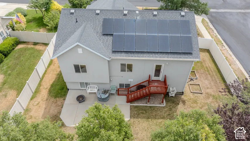 Rear elevation featuring solar panels, a gabled roofline, and a concrete patio
