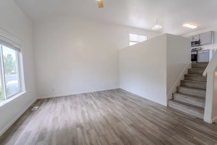 Spacious living area featuring wood-finish flooring, high vaulted ceilings, and large windows