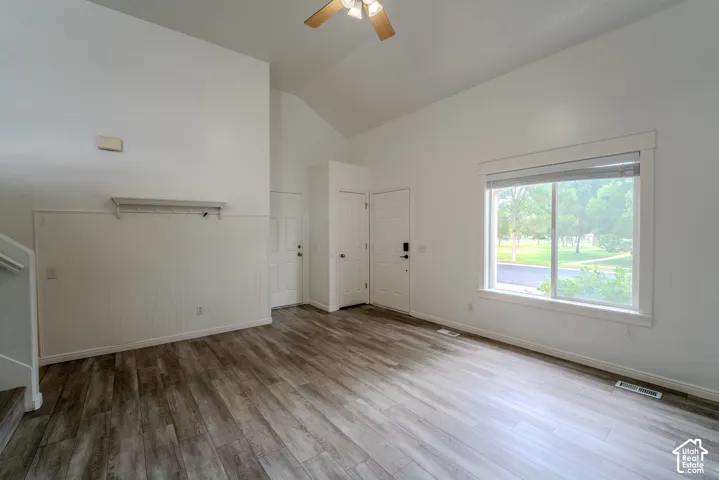 Spacious living area featuring wood-finish flooring and a vaulted ceiling