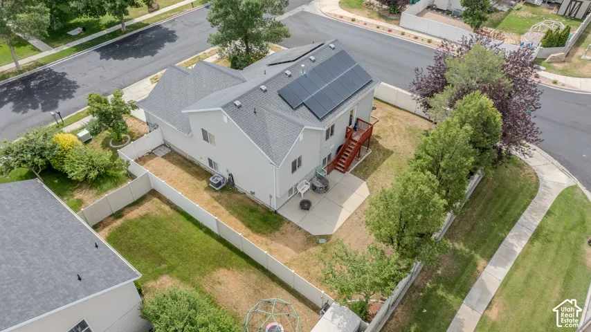 Rear elevation featuring a concrete patio, wood deck, and solar panels