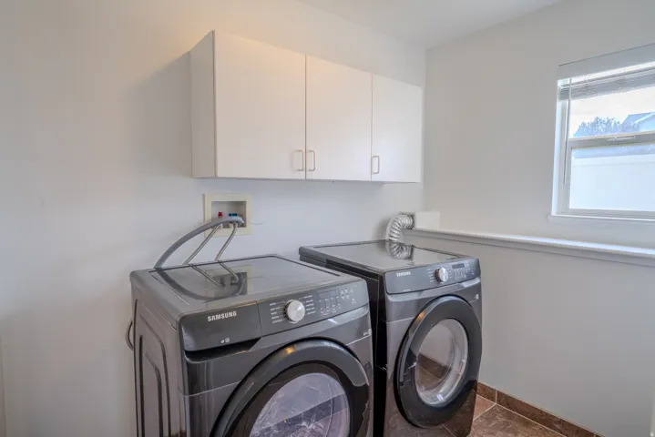 Laundry area featuring white cabinetry, a window with natural light, a utility hookup, and a tiled floor