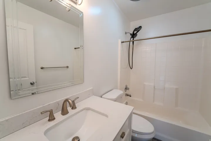 Bathroom featuring a vanity with a white countertop and undermount sink, brushed nickel faucet, framed mirror, and a tub/shower combination with white subway tile surround