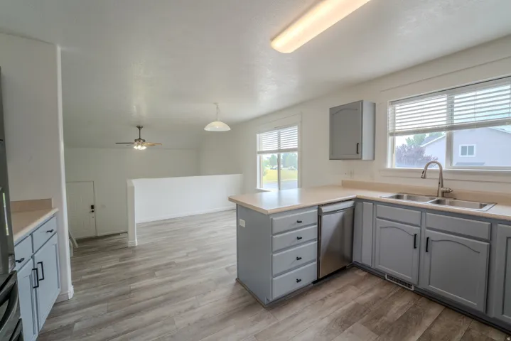 Kitchen featuring gray cabinetry, a stainless steel double basin sink, and a built-in dishwasher