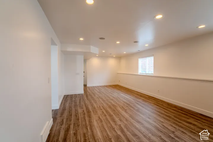 Spacious room featuring wood-finish flooring, recessed lighting, and a window with blinds