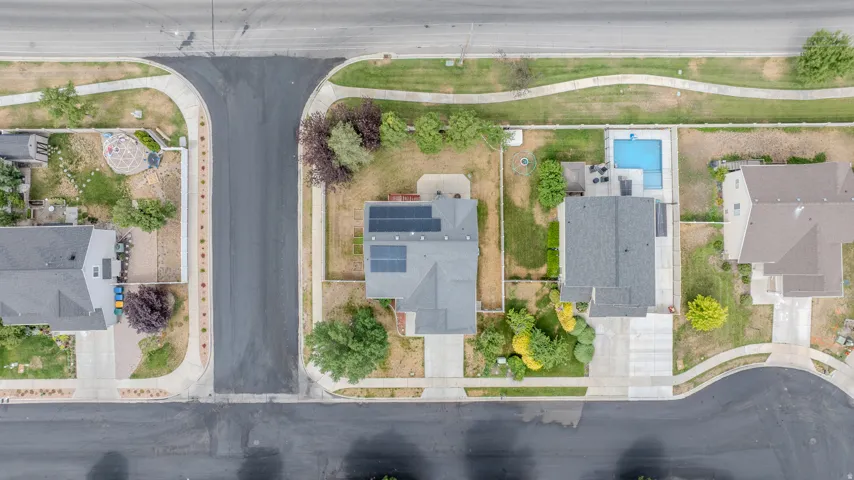 Aerial perspective showcasing a residential property with a private swimming pool, concrete patio, and mature landscaping