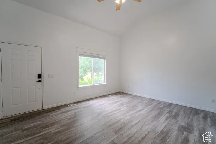 Spacious room featuring vaulted ceilings, a contemporary ceiling fan, and wood-finish flooring