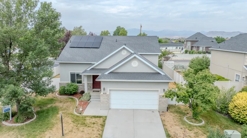 Contemporary stucco residence featuring an attached two-car garage, solar panel array, and a covered front entry