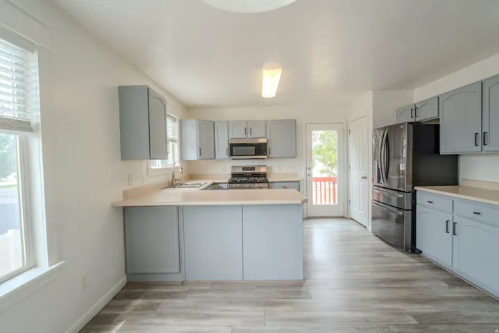 Kitchen featuring light blue cabinetry, light-toned countertops, and wood-finish flooring