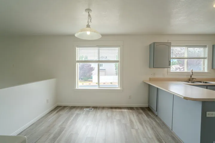 Open-concept area featuring light wood-finish flooring, white walls, and a modern pendant light fixture