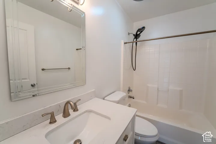 Bathroom featuring a vanity with a white countertop and undermount sink, brushed nickel faucet, framed mirror, and a tub/shower combination with white subway tile surround