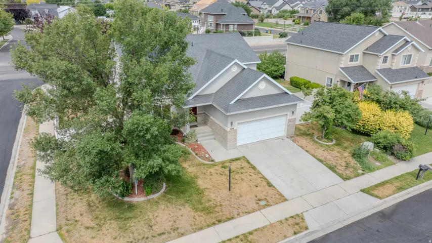 Two-story residence featuring a two-car garage, concrete driveway, and a mature front yard tree