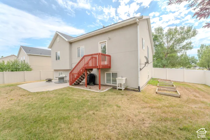 Expansive backyard featuring a concrete patio, privacy fencing, and raised garden beds
