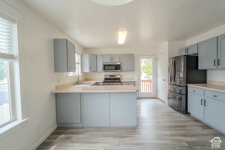 Kitchen featuring light blue cabinetry, light-toned countertops, and wood-finish flooring