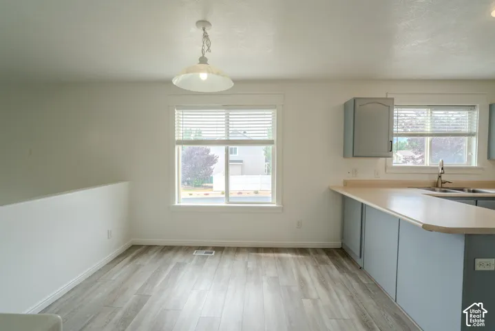 Open-concept area featuring light wood-finish flooring, white walls, and a modern pendant light fixture