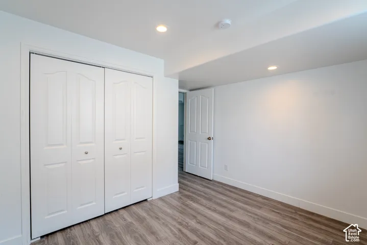 Interior room featuring wood-finish flooring, white walls, and recessed lighting