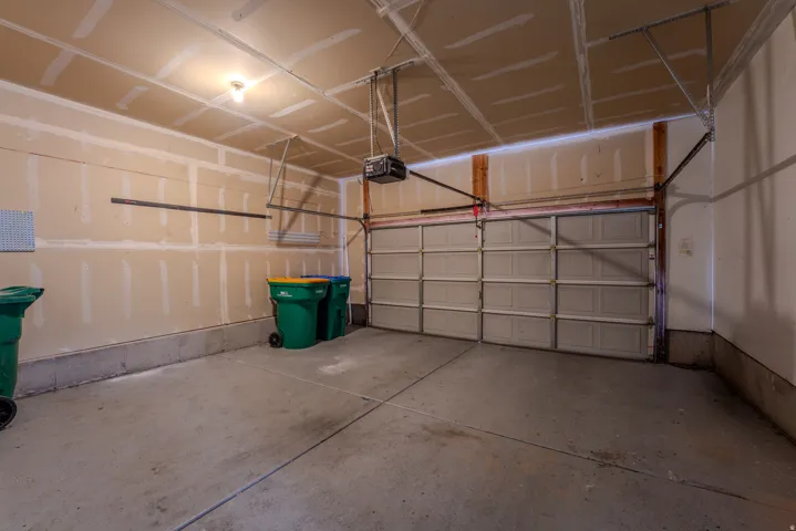Spacious garage featuring a sectional garage door, concrete flooring, exposed ceiling joists, and a garage door opener system