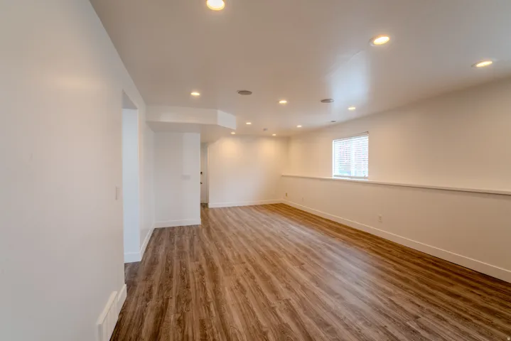 Spacious room featuring wood-finish flooring, recessed lighting, and a window with blinds