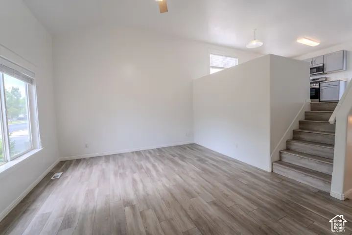 Spacious living area featuring wood-finish flooring, high vaulted ceilings, and large windows