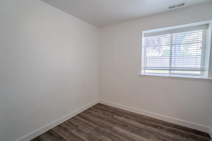Room featuring wood-finish flooring, white baseboards, and neutral wall paint