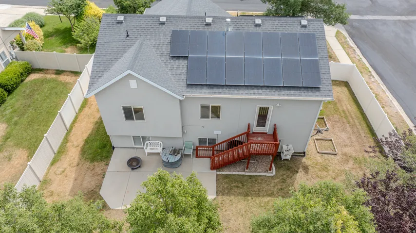 Rear elevation featuring solar panels, a gabled roofline, and a concrete patio