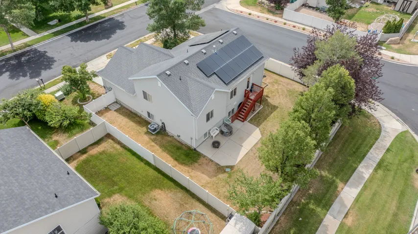 Rear elevation featuring a concrete patio, wood deck, and solar panels