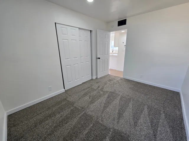 Neutral gray carpeting with white baseboards and walls