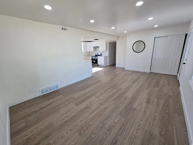Open-concept living space with wood-finish flooring, recessed lighting, and bright white walls
