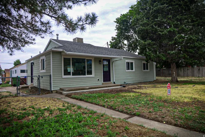 Light green siding exterior with a dark asphalt shingle roof
