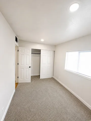 Bedroom featuring neutral carpeting, white walls, and a window with blinds