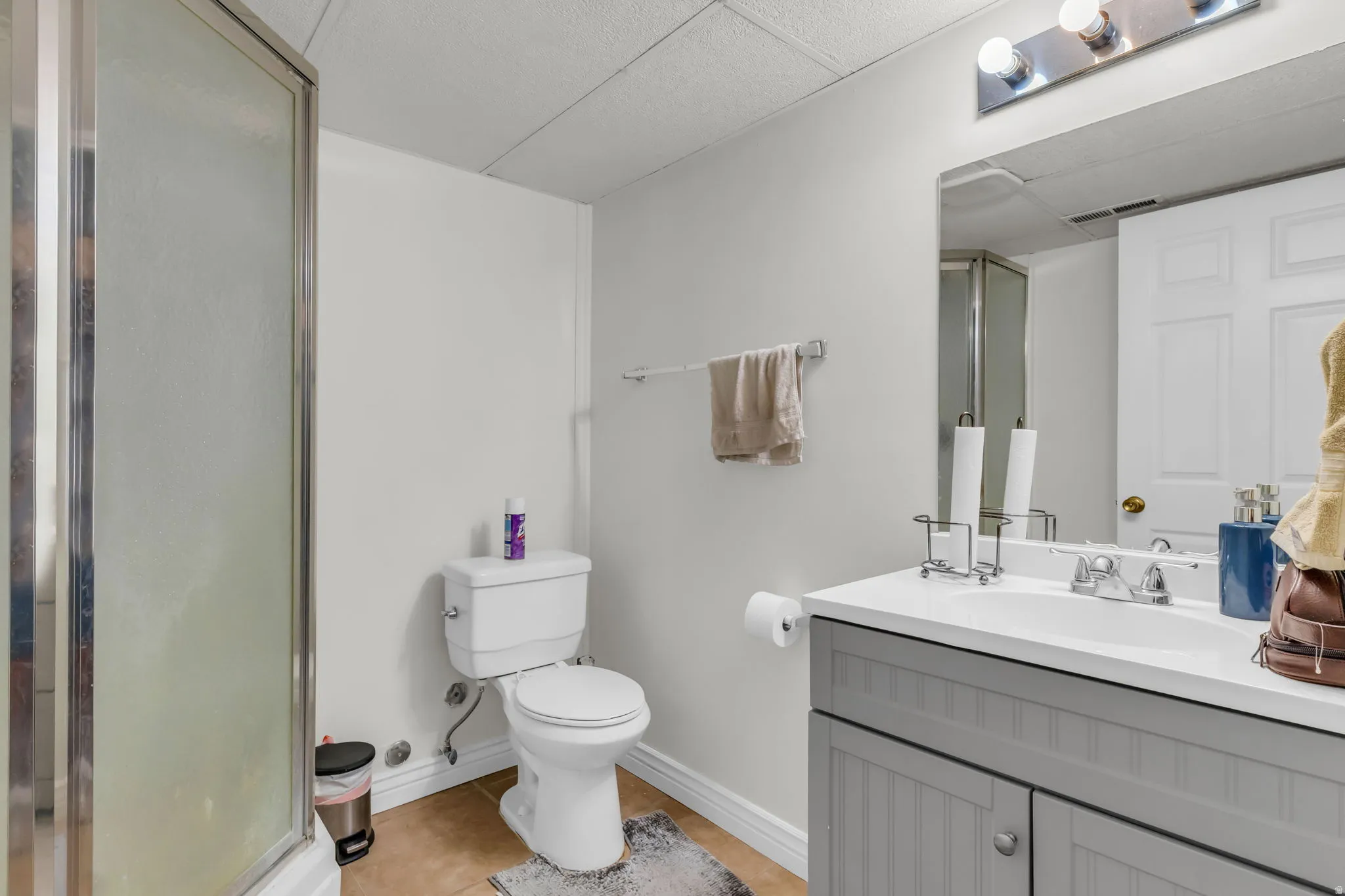 Bathroom featuring a glass-enclosed shower, a vanity with a white countertop, and a built-in sink