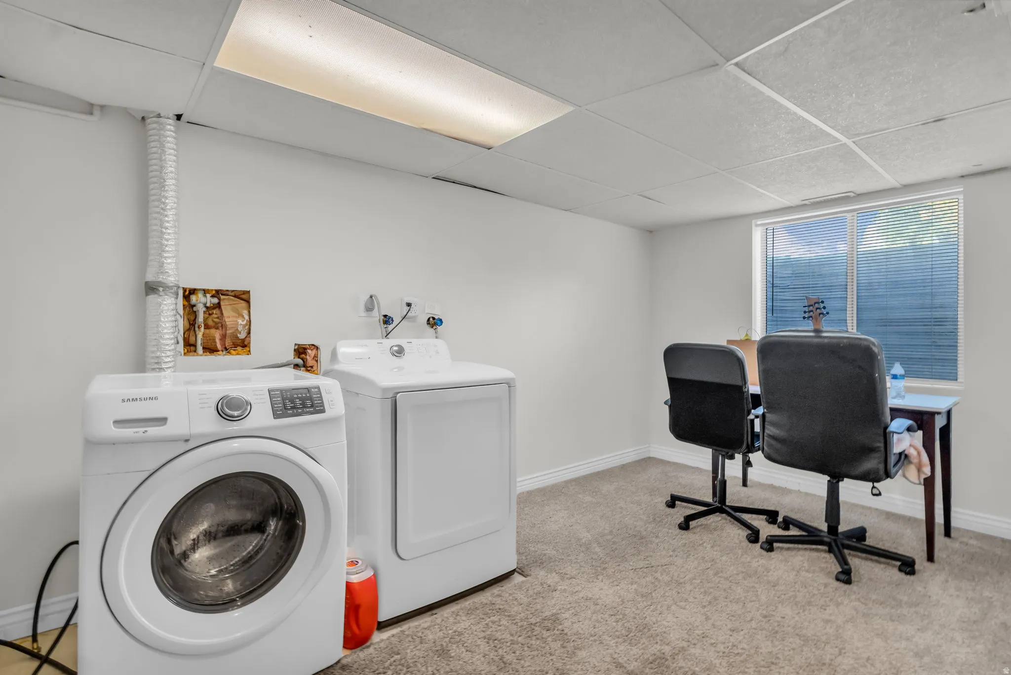 Laundry area featuring a drop ceiling, window, and wall-mounted plumbing for appliances