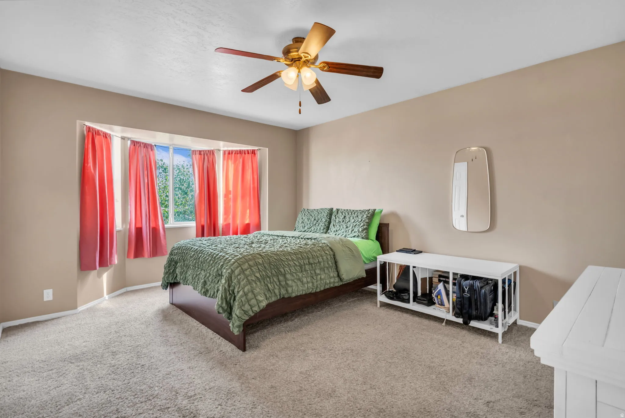 Bedroom featuring a bay window, ceiling fan with integrated lighting, and neutral carpeting