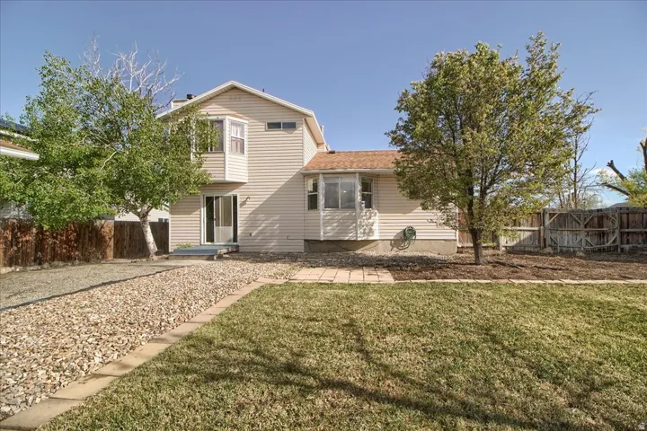 Expansive backyard featuring a manicured lawn, a gravel pathway, and mature trees