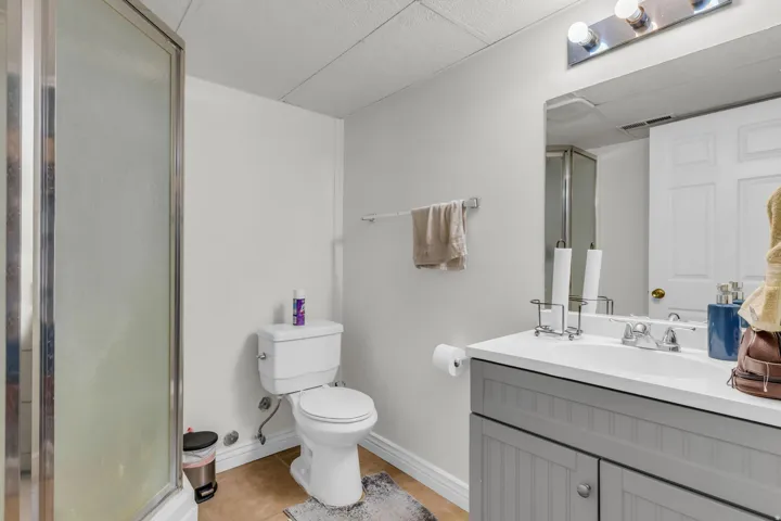 Bathroom featuring a glass-enclosed shower, a vanity with a white countertop, and a built-in sink