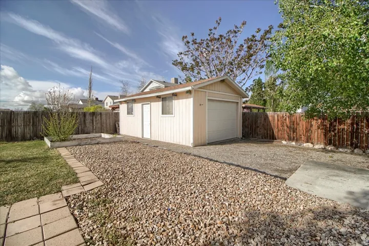 Detached single-car garage featuring vertical siding, an overhead door, and a separate entry door
