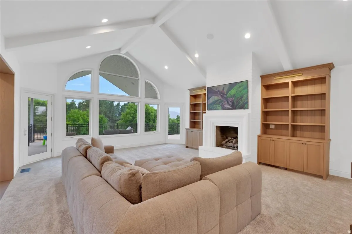 Vaulted ceilings with exposed beams, recessed lighting, and expansive arched windows