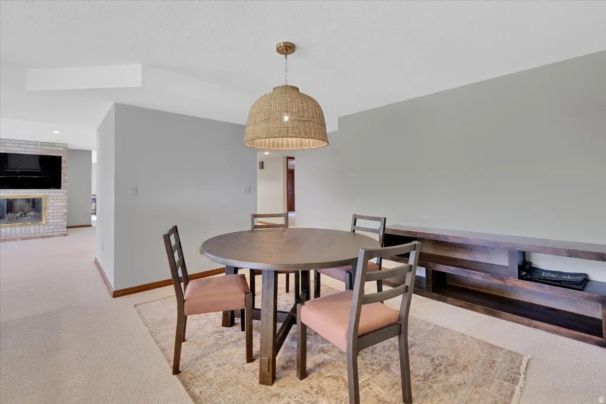 Dining area featuring a woven pendant light fixture, a built-in wood-finish media console, and light-toned carpeting