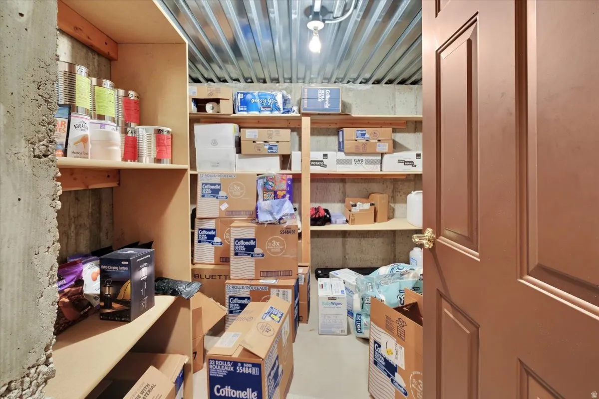 Utility room featuring concrete walls, a corrugated metal ceiling, and built-in wood shelving for storage