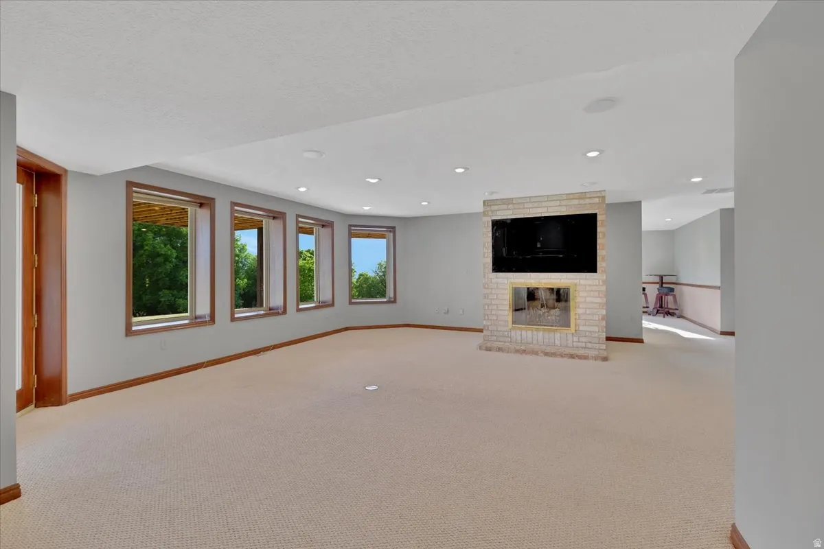 Expansive lower-level room featuring a light brick-faced fireplace with an integrated television niche