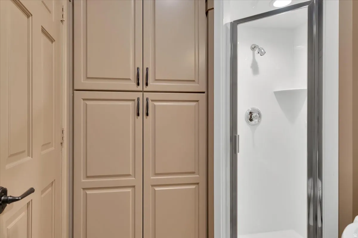 Integrated shower with glass enclosure, chrome fixtures, and a corner shelf