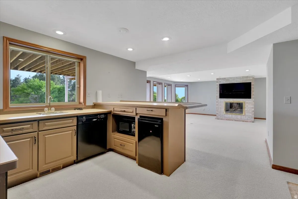 Lower-level entertainment space featuring a wet bar with built-in cabinetry, sink, and compact refrigerator