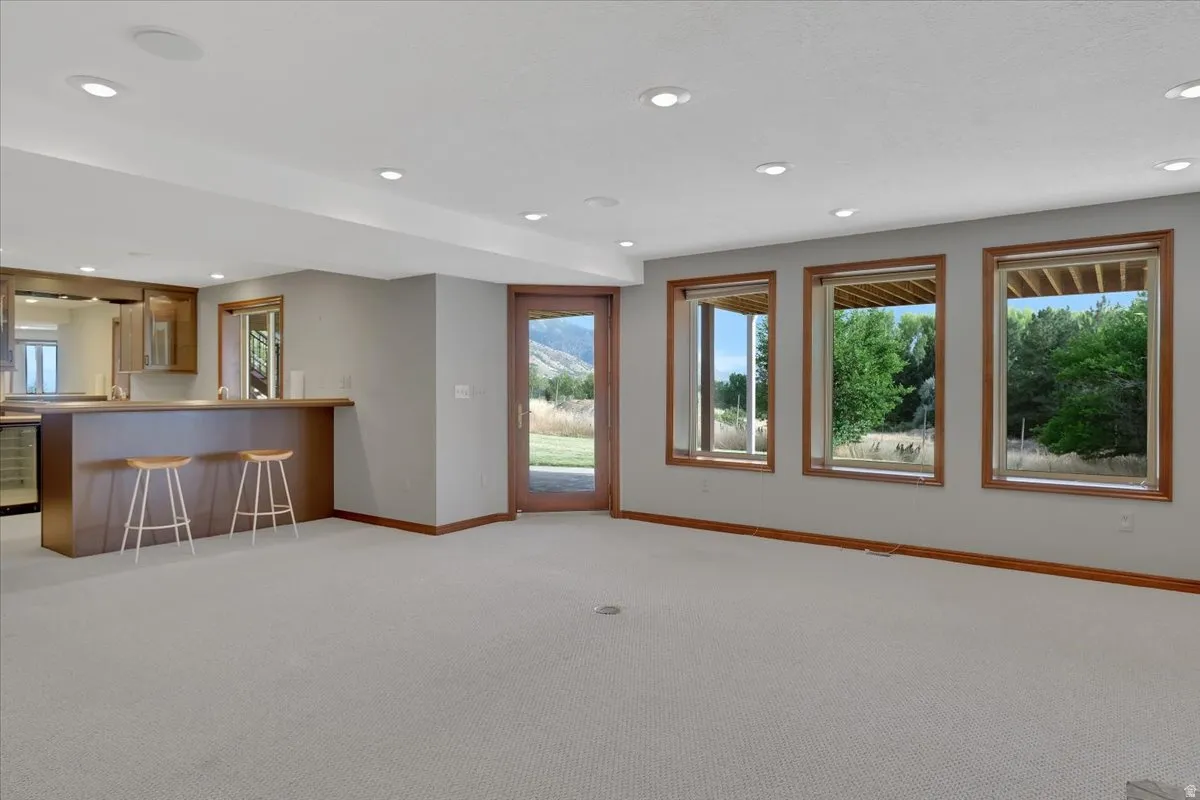 Spacious recreational room featuring a built-in wet bar with wood cabinetry, integrated beverage refrigerator, and a light-toned countertop