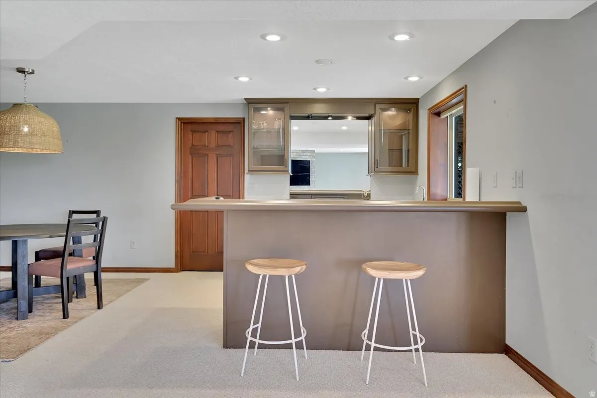 Integrated wet bar featuring upper glass-front cabinetry, recessed lighting, and a built-in counter